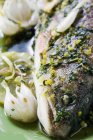 Peixe frito com alho, ervas e limão em prato verde — Fotografia de Stock