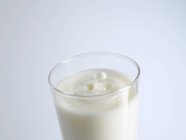 Bicchiere di latte con gocce di latte — Foto stock