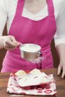 Mujer rociando azúcar glaseado sobre magdalenas - foto de stock