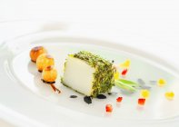 Соленая треска с травяной корочкой и сладкими луковицами на белой тарелке — стоковое фото