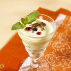 Closeup view of mango cream with berries and leaves in glass — Stock Photo