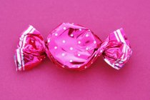 Nahaufnahme von Bonbons in gepunkteter Verpackung auf rosa Hintergrund — Stockfoto