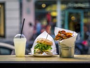 Vista laterale di un hamburger con limonata e patatine fritte in un ristorante fast food — Foto stock