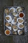 Raw oysters in shells with condiments — Stock Photo