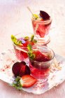 Detox drinks with strawberries and beetroot in glasses over plate — Stock Photo