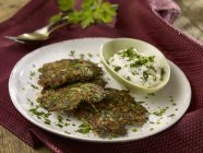 Courgette fritters with herb quark on white plate over towel — Stock Photo