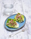 Avocado with bacon and radishes on lettuce leaves on wooden surface — Stock Photo