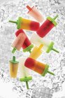 Various ice lollies on ice cubes — Stock Photo