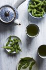 Edamame snacks served with tea over wooden surface — Stock Photo
