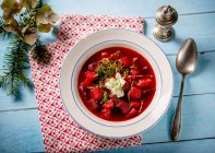 Borscht with sour cream on white plate over towel — Stock Photo