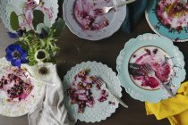 Top view of leftovers of blueberry pie on various plates and flowers — Stock Photo