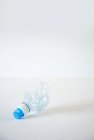 Elevated view of squashed water bottle on white surface — Stock Photo