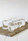 Vasos de agua sobre tabla de cortar de madera - foto de stock