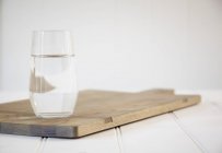 Glass of water on a chopping board — Stock Photo