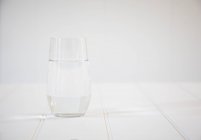 Склянка води на білому дерев'яному столі — стокове фото