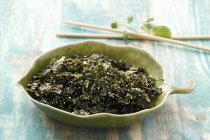 Fried seaweed with sesame seeds in green bowl — Stock Photo