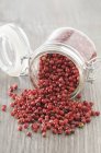 Pink peppercorns on wooden surface — Stock Photo