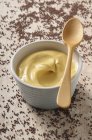 Bowl of mustard with wooden spoon — Stock Photo