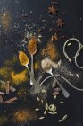 An arrangement of spices with spoons and string on a black surface — Stock Photo