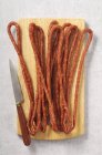 Long salami fin sur planche de bois — Photo de stock