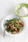 Chicken with mange tout and chillis on white plate with fork — Stock Photo