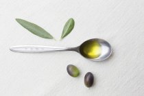 Ложка оливкової олії з оливками — стокове фото