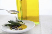 Оливковое масло льется на листья — стоковое фото