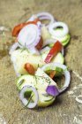 Anelli di cipolla, patate affettate, fette di zucchina e peperoni su un tagliere di legno — Foto stock