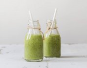 Green smoothies with avocado in bottles — Stock Photo