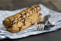 Caramel eclair on plate with fork — Stock Photo