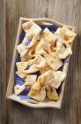 Top view of Bugnes deep-fried French pastries with tissues in wooden tray — Stock Photo