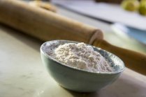 Vue rapprochée de farine dans un bol en céramique avec rouleau à pâtisserie — Photo de stock