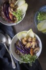 Trigo sarraceno, verduras, semillas de sésamo tofu y berro en cuencos sobre una mesa de madera con un paño de lino y cucharas vintage - foto de stock