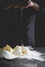 Visão cortada de um homem travando um ovo para montão de farinha e manteiga — Fotografia de Stock