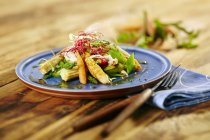 Восточные овощи с полосками куриной грудки на голубой тарелке над деревянной поверхностью — стоковое фото