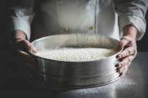 Cropped view of a confectioner with a large sieve of icing sugar — Stock Photo