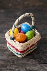 Vista de cerca de huevos de colores en una canasta para Pascua - foto de stock