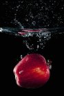 Maçã vermelha caindo na água — Fotografia de Stock