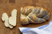 Closeup top view of sliced poppyseed plait on wooden surface — Stock Photo