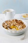 Closeup view of peach Crumble with spoon in baking dish — Stock Photo