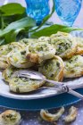 Vegetarian wild garlic pastries on a plate with a pair of pastry tongs and fresh wild garlic — Stock Photo