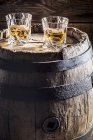 Two glasses of Whisky with ice on old wooden barrel — Stock Photo