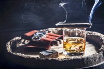 Fumar cigarro sobre un vaso de whisky - foto de stock