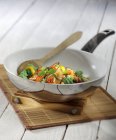 Stir-fried gilthead seabream and vegetables in pan over mat — Stock Photo