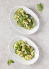 Courgette with basil and pine nuts  on white plates — Stock Photo