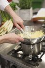Cropped view of hands mixing Bechamel sauce in a bowl with a whisk — Stock Photo
