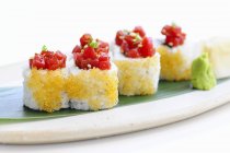 Ura-maki with tomato coulis and flying fish roe on desk on white surface — Stock Photo