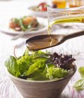 Öl vom Löffel auf den Salat gießen — Stockfoto