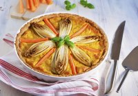 Chicory and carrot tart in a baking dish on a tea towel — Stock Photo