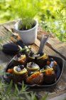 Aubergines  la Provenal on black plate over wooden desk outdoors with grass on background — Stock Photo